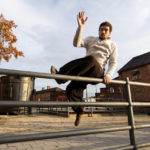 Traceur balancing above metal rails during Sheffield parkour training