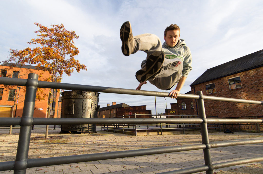 Traceur vaulting a handrail in an autumn Sheffield courtyard