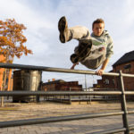 Traceur vaulting a handrail in an autumn Sheffield courtyard