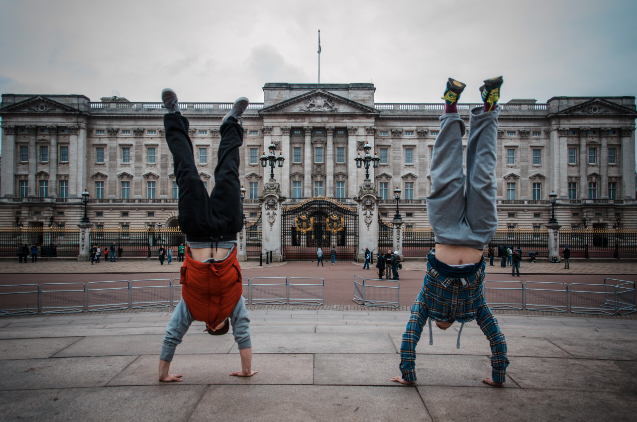Two traceurs holding handstands together in a city square