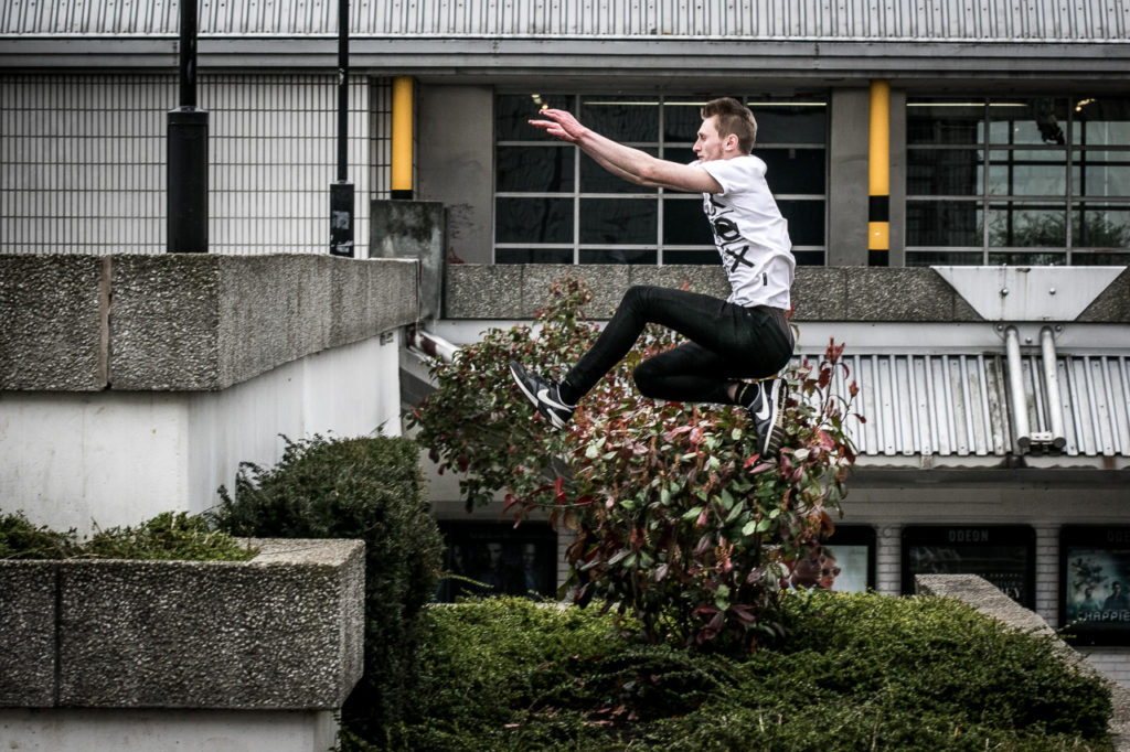 Traceur jumping over a concrete planter during Sheffield parkour training