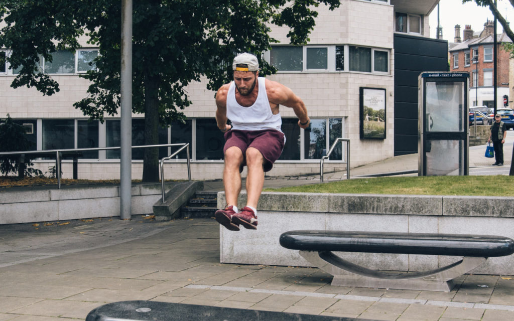 Traceur vaulting a curved rail in a Sheffield city square