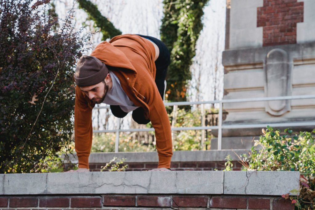 young man doing parkour stunt on stone border